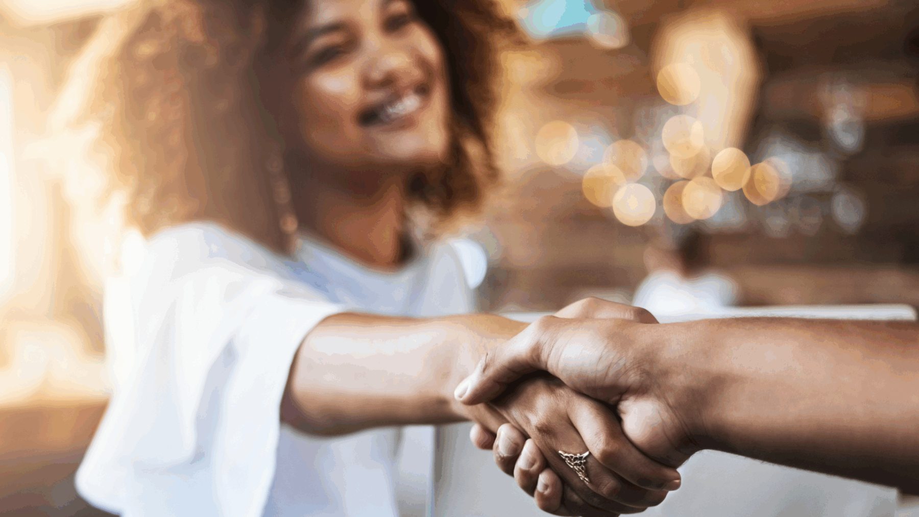 Upselling strategies for freelancers shown by a woman freelancer shaking hands with a client after agreeing to a premium package in a modern office.