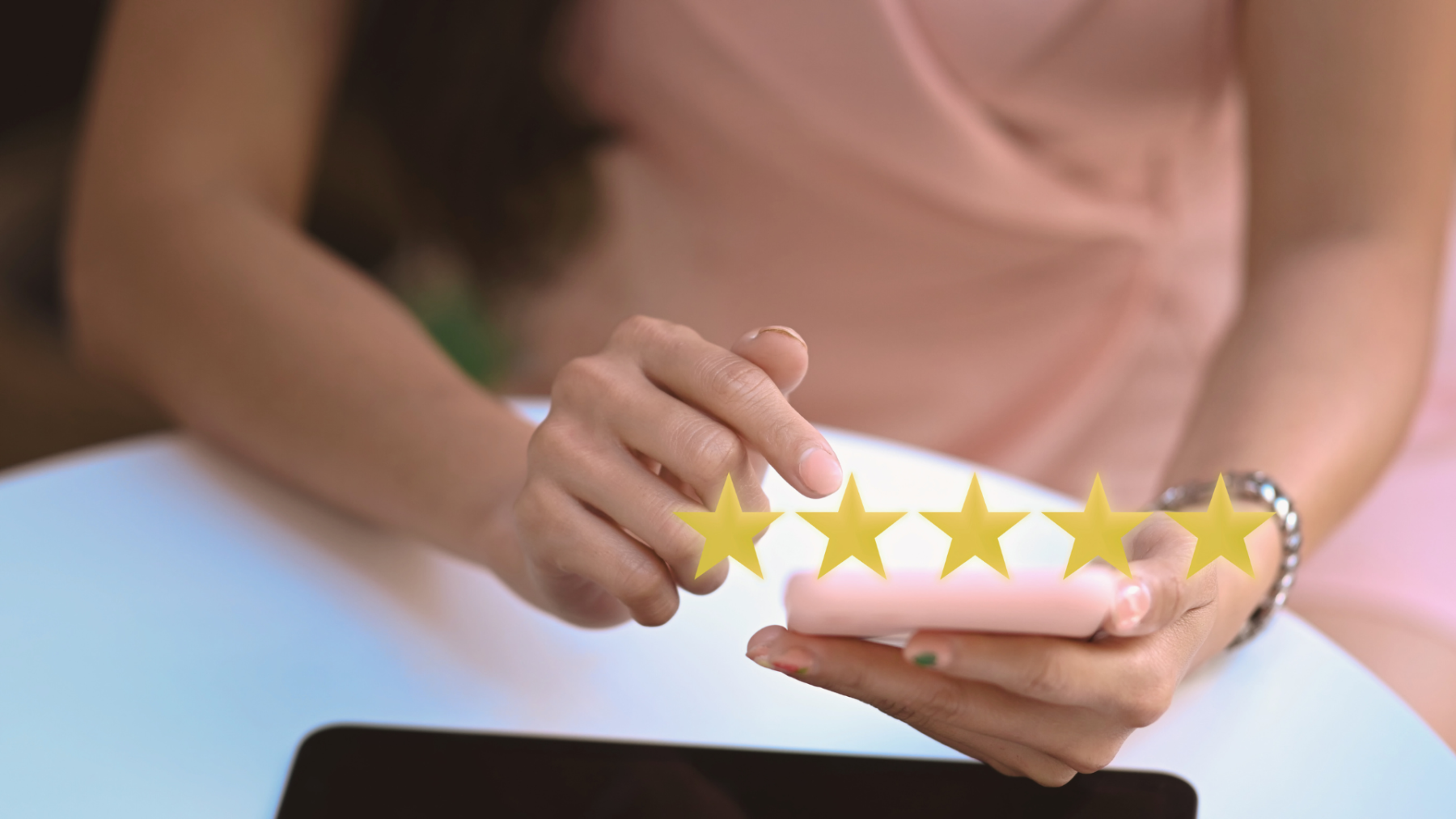 How to ask clients for reviews, illustrated by a person tapping a five-star rating on a phone review screen at a desk with a laptop.