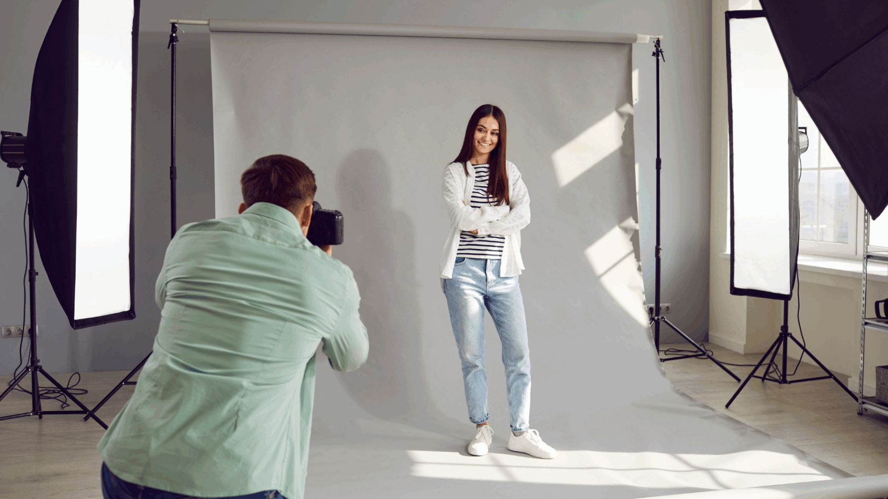 Professional company headshots session in a well-lit studio: a photographer frames a woman’s portrait against a neutral backdrop with soft key lighting.