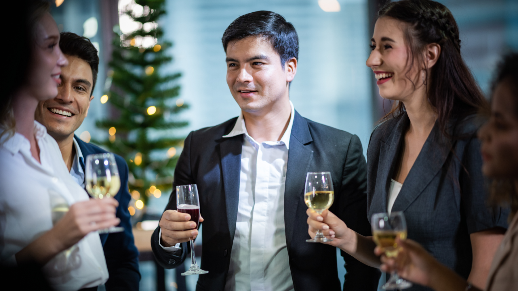 Company employees smiling and toasting at a festive holiday party, captured during a holiday corporate photography session.
